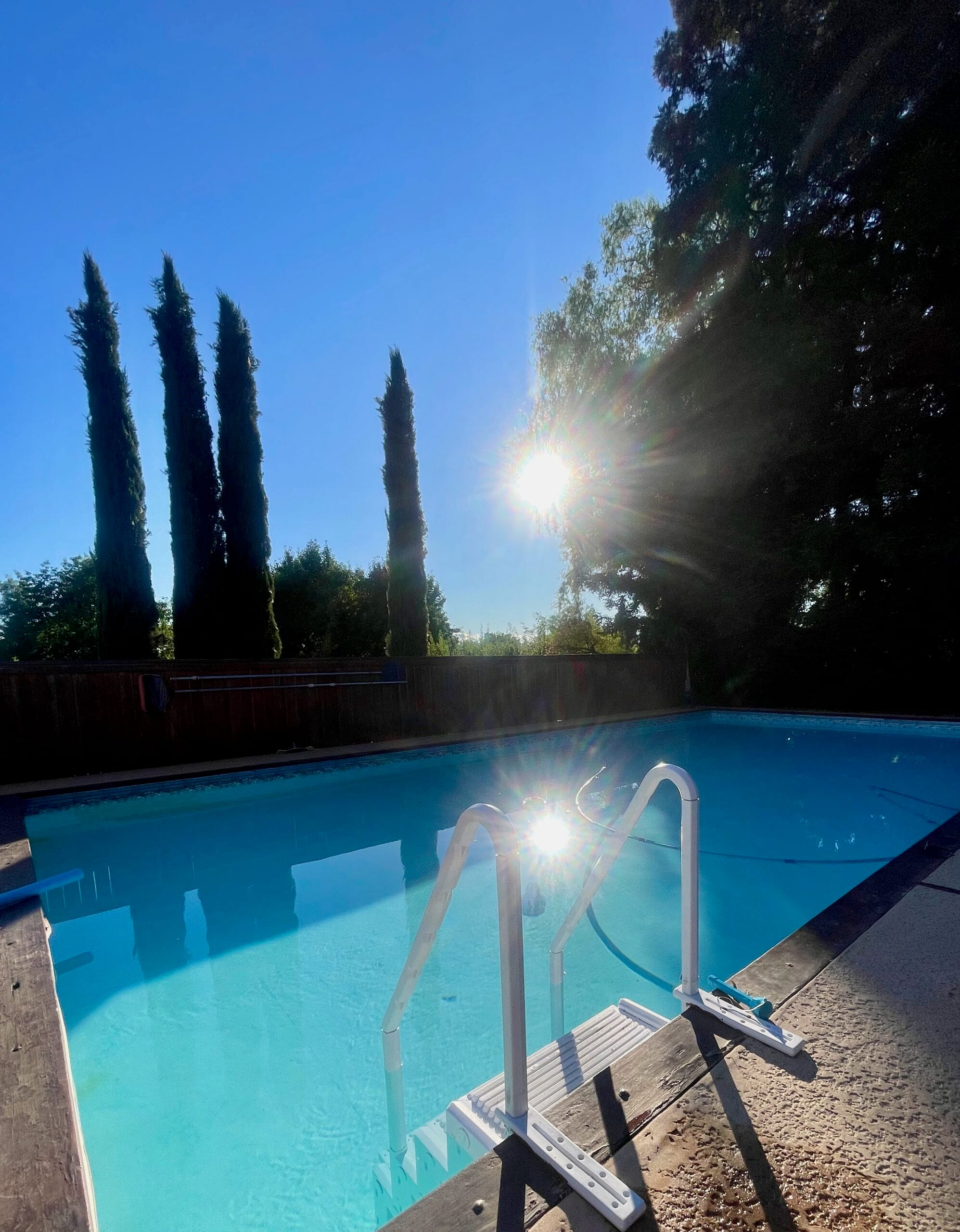 a pool with stairs and trees in the background